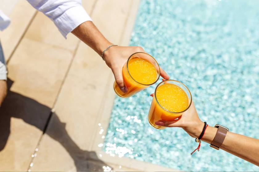 Persones brindant amb suc de taronja en una piscina