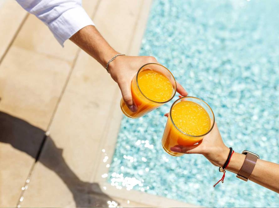 Persones brindant amb suc de taronja en una piscina